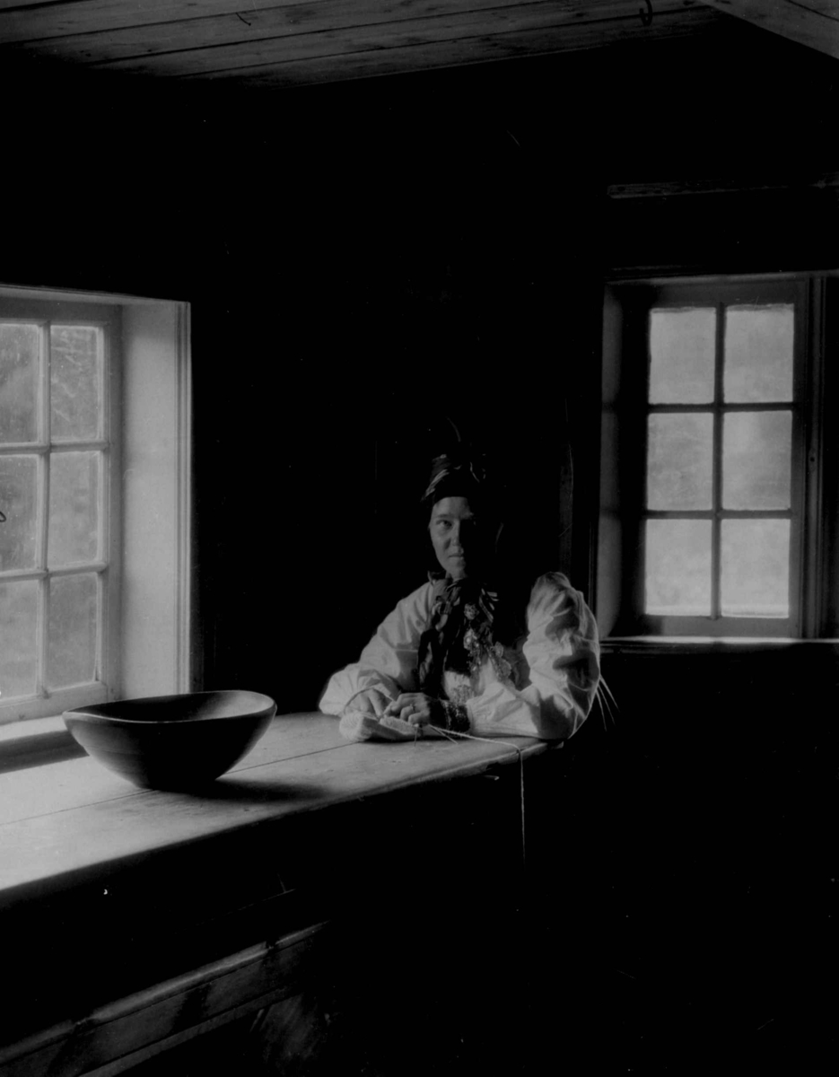 Kvinnedrakt fra Rust, Eggedal. Over 100 år gammel. Interiør. Kvinne sittende ved bord. 