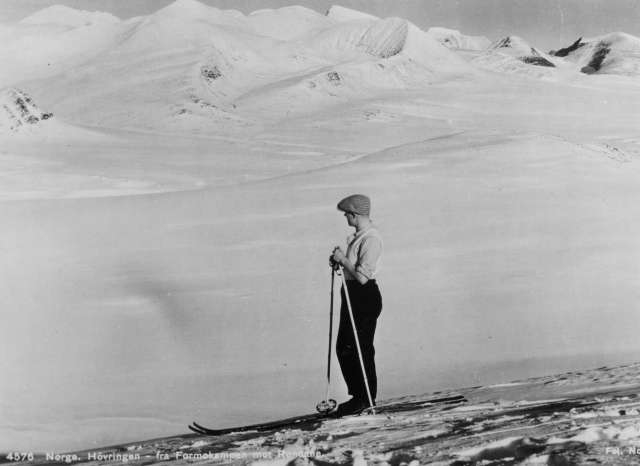 Avfotografert postkort. En enslig skiløper skuer utover snødekt fjellandskap ved Høvringen. Utsikt fra Formokampen mot Rondane.