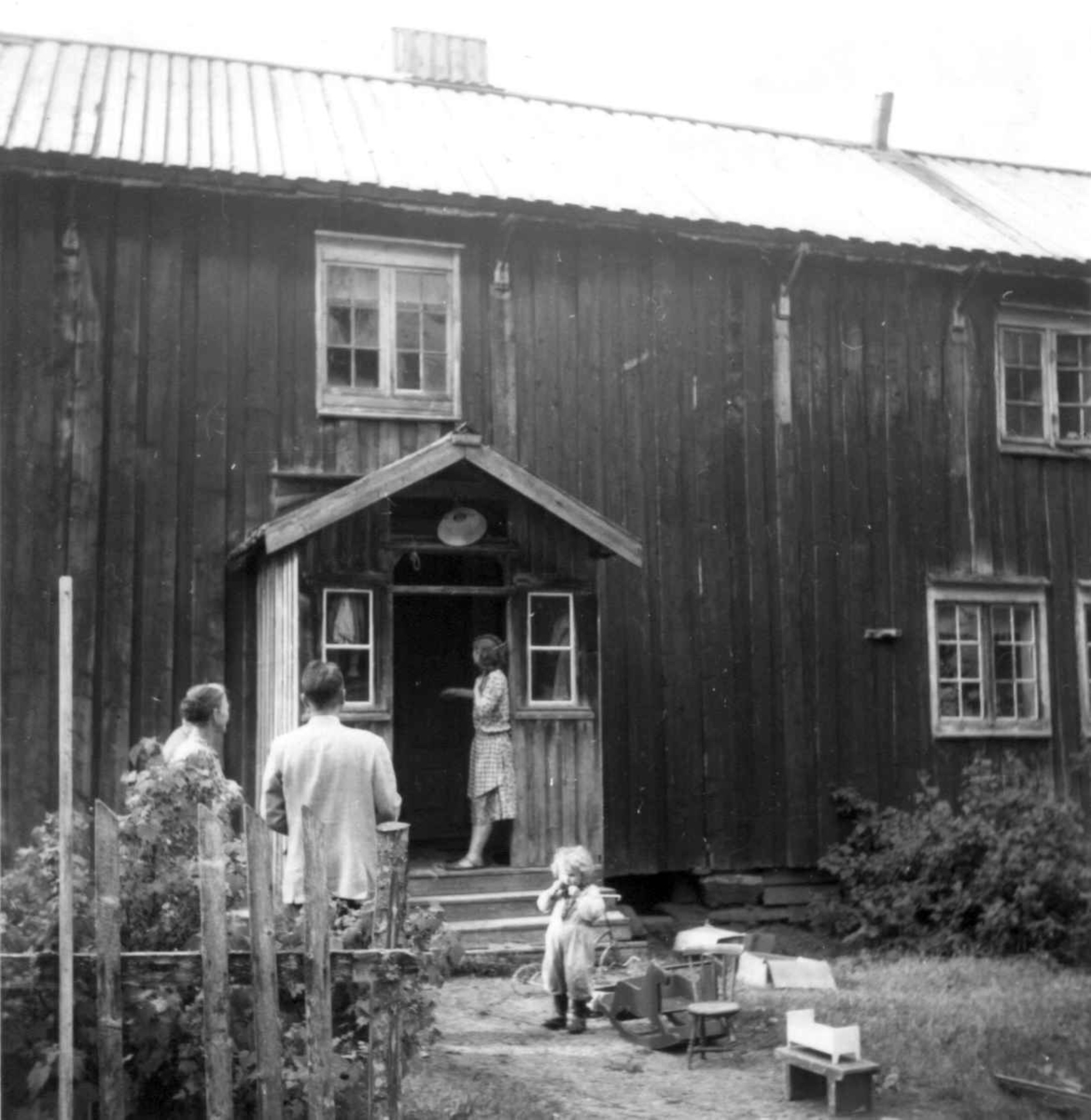 Gård i Rana, med fire personer utenfor hovedhuset. 1954. 
