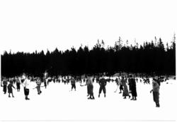 Tryvann skøytebane, 1934. Skøyteløpere i sving på isen. Noen