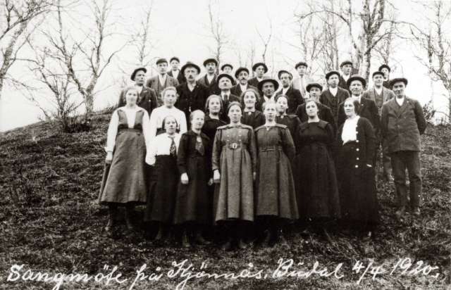 Kvinne og mannsdrakt, Budalen, Sør-Trøndelag 1920. Gruppe mennesker i bakkehelling. Bildet påskrevet: "Sangmöte på Kjönnås, Büdal 4/4 1920".