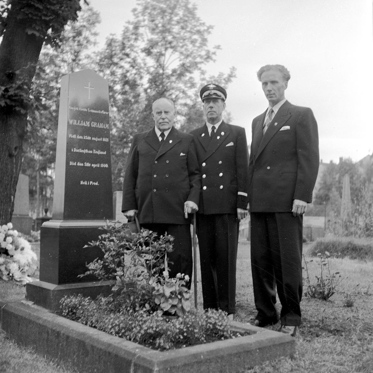 Serie. William John Graham, Rolf Wilhelm Graham og Jonny Graham legger ned krans på William Grahams gravplass. Fotografert 1. sept. 1954.