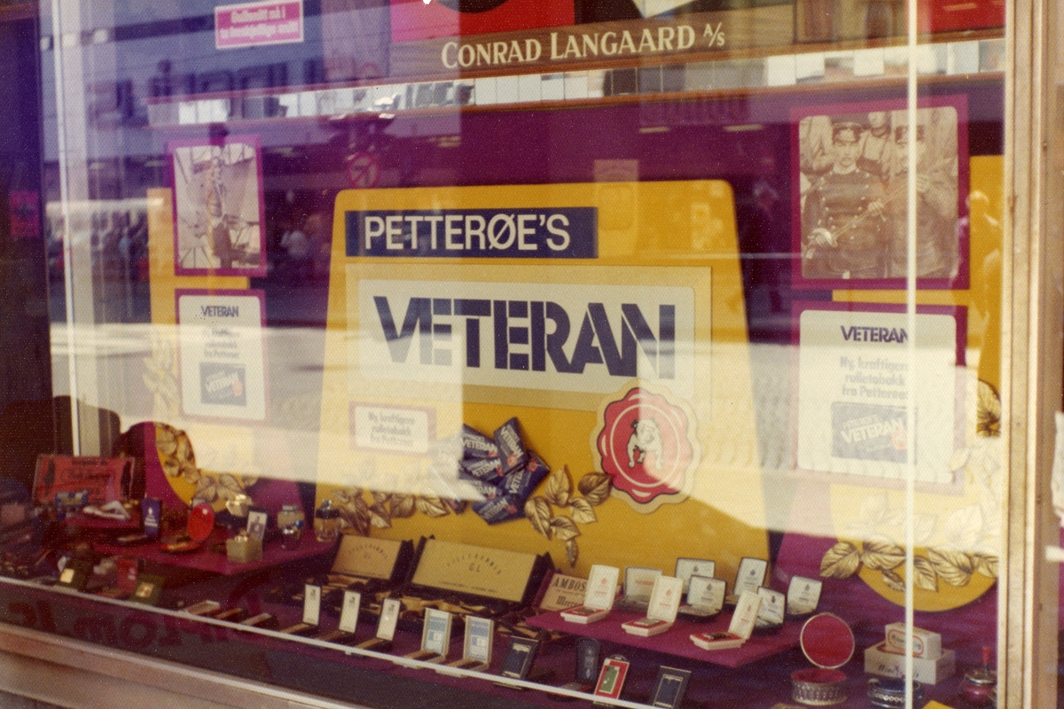 Vindusutstilling med reklame for Petterøes Veteran rulletobakk hos tobakksbutikk på Storgata i Oslo.