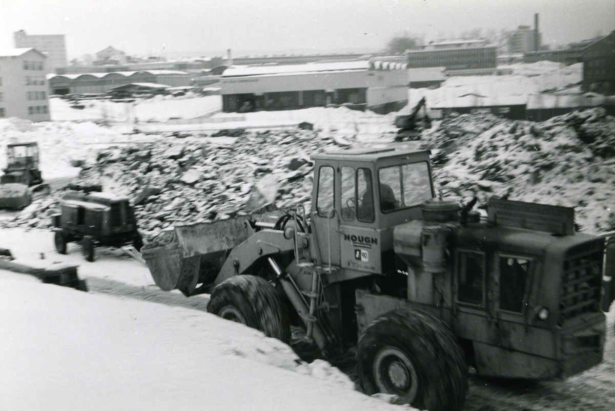 Byggeplass.
Konstruksjon av Tiedemanns Tobaksfabrik på Hovin i 1967. En gravemaskin av merket Hough i arbeid på byggeplassen.