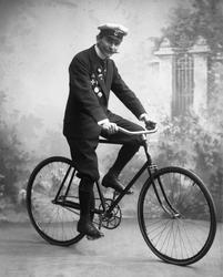 Portrett, mann med uniformslue, medaljer og sykkel.