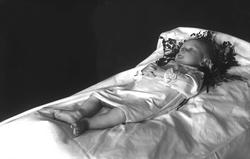 Post mortem-fotografi. Dødt barn i seng.