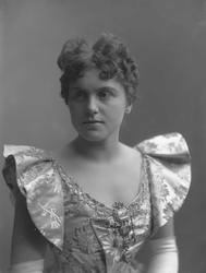 Portrett, ung kvinne med kjole, smykke på lav utringning.