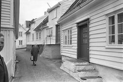 Fra Karmøy august 1965. Kvinne som går i en trang boligvei i