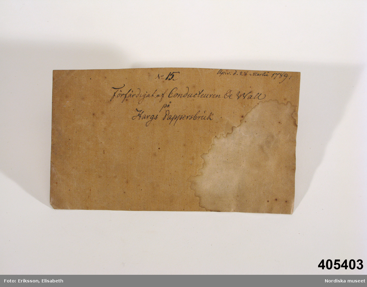 Pappersprov, kartong, en bit med text: "Upw. D. 28 Martii 1789" samt "No 15 Förfärdigat af Conducteuren De Wall på Hargs Pappersbruk".

Pappersprovet låg ursprungligen i ett brunt omslagspapper (ej förvärvat) tillsammans med färgningsprover (se inv.nr 405.402a-d). Omslagspapperet var hopvikt 340 x 220 cm, mycket söndrigt, med två små etiketter med handskrivet "No 23" och 2 större etiketter med text. På den vänstra: "Prof af Hargs pappersbruks tillwerkning år 1789. Af conducteur De Wall." och på den högra: " Prof på färgning med Svenska lafarter år 1803. Af Joh. P. Westman, Norrköping" (obs namnet Westring felskrivet)
/Elisabet Hidemark/
/Berit Eldvik 2008-03-25