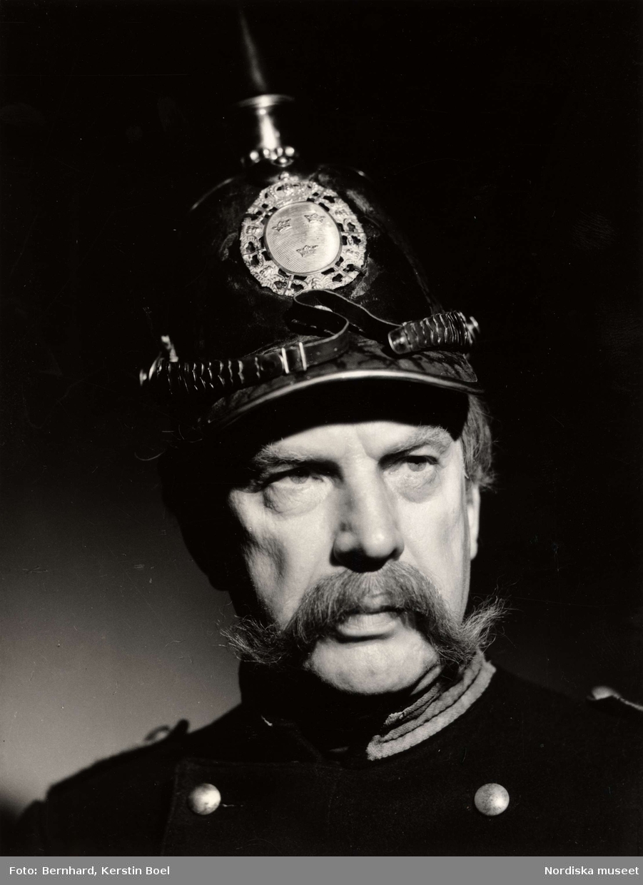 Porträtt av skådespelaren Sven Bergvall med pickelhuva på huvudet.