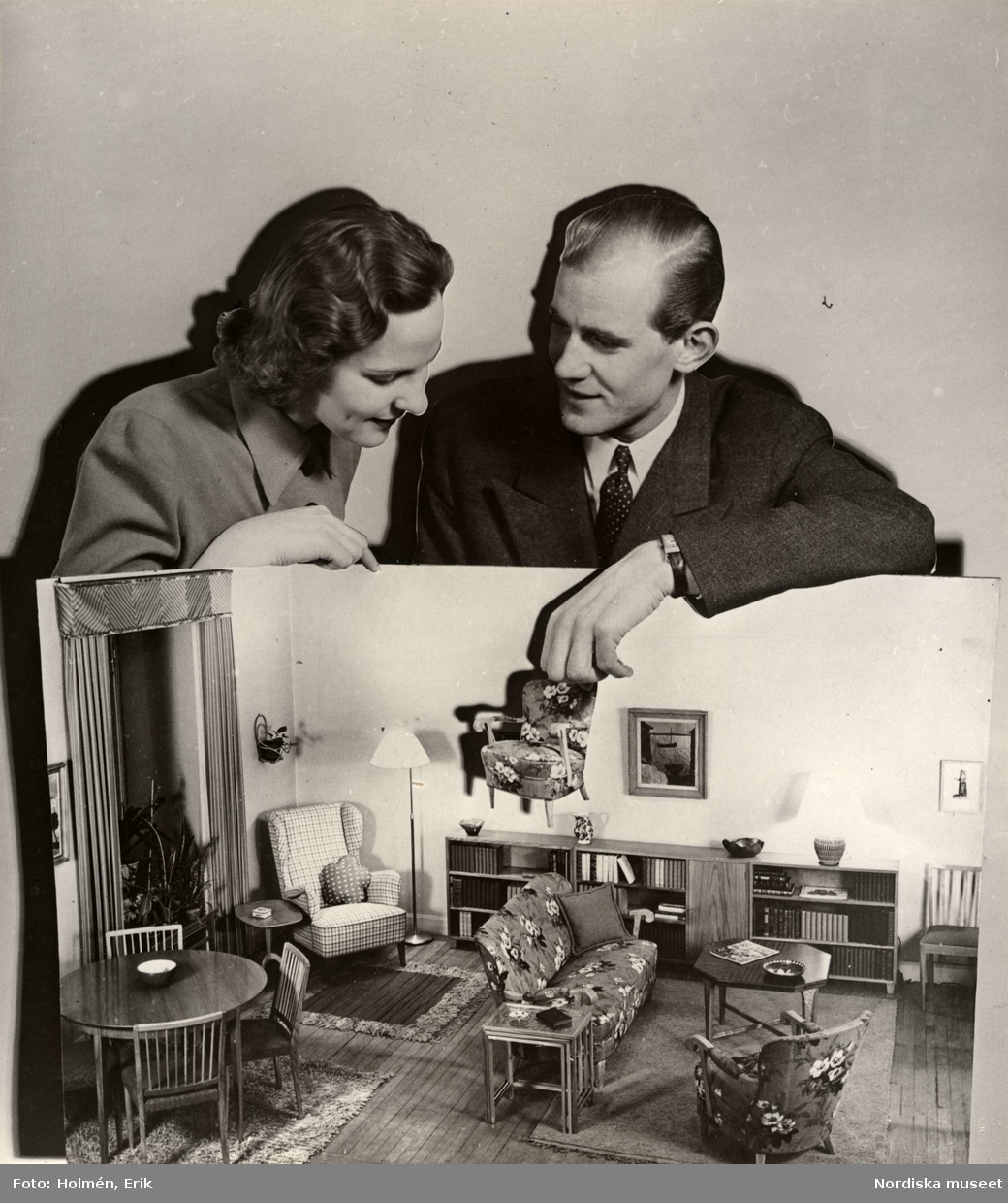 Utställningen Brud och hem på varuhuset Nordiska Kompaniet i Stockholm 1944. Man och kvinna med modell av en möblerad lägenhet.