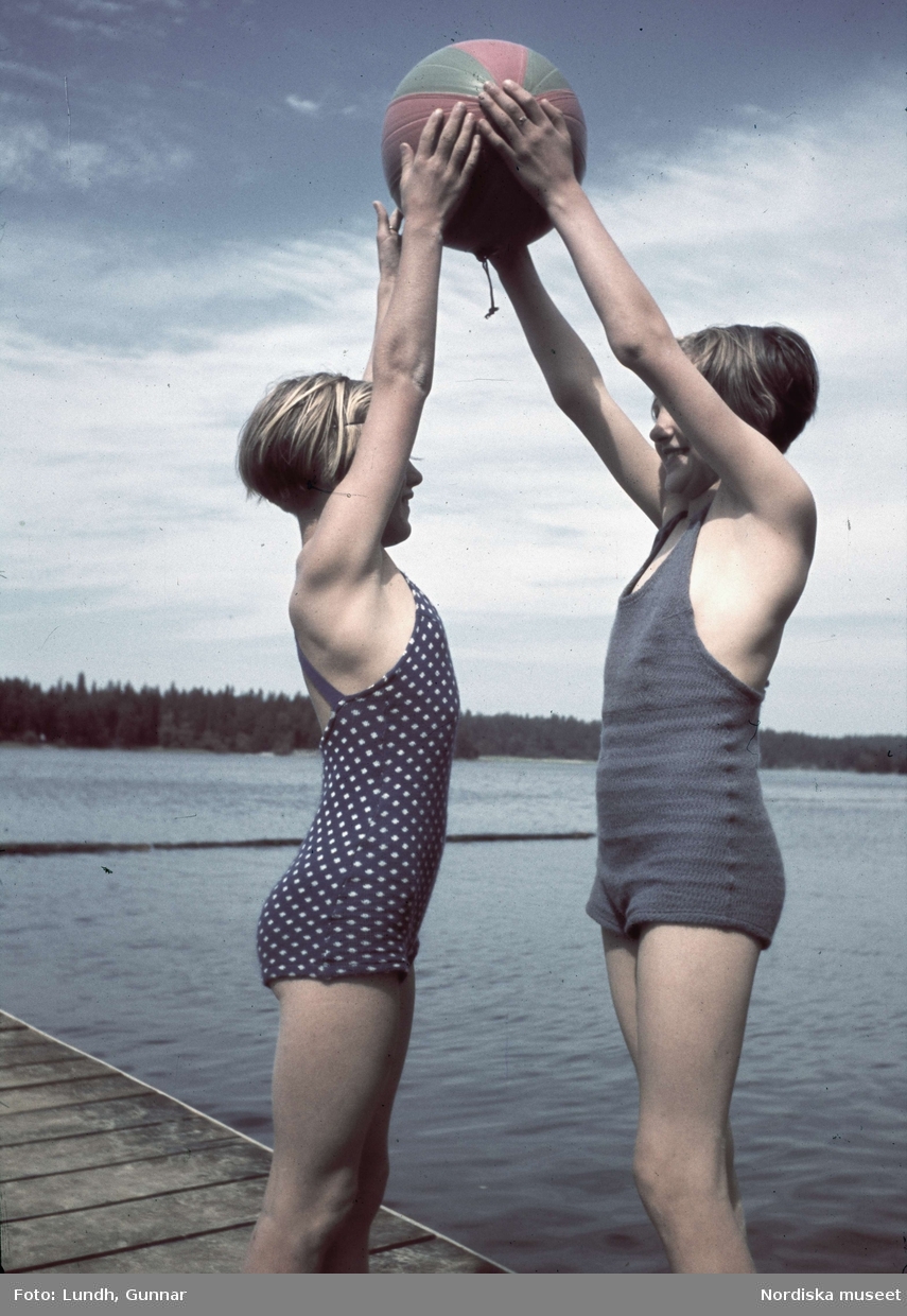 Två flickor håller en badboll med uppsträckta händer. Mälarhöjden, Stockholm