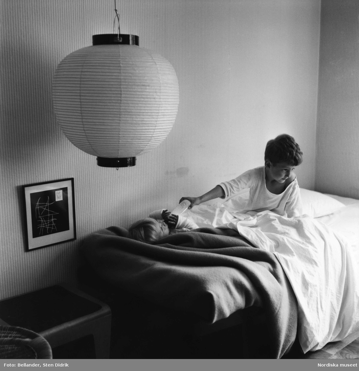 Fotografens son ger sin lillasyster nappflaskan en morgon i sängen.