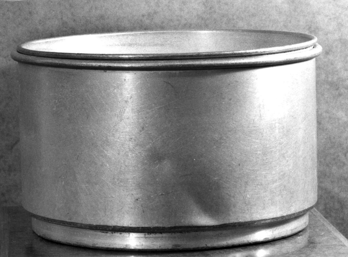 Apparat av aluminium för silning och kylning av mjölk. Hela apparaten består av sju delar:
1) ring för applicering på mjölkflaska.
2) kyldel, konisk, med dubbla väggar, avtappningskran av mässing, tillflödesskiva, gummislang.
3) mellankärl med små hål för att få mjölken att rinna längs väggarna i del 2
4) mjölksil med stort hål för att få mjölken att rinna längs väggarna i del 2
5) silplatta med många fina hål
6) silplatta med grövre och färre hål
7) ring för fasthållande av filter och sil, ett antal pappersfilter medföljer.