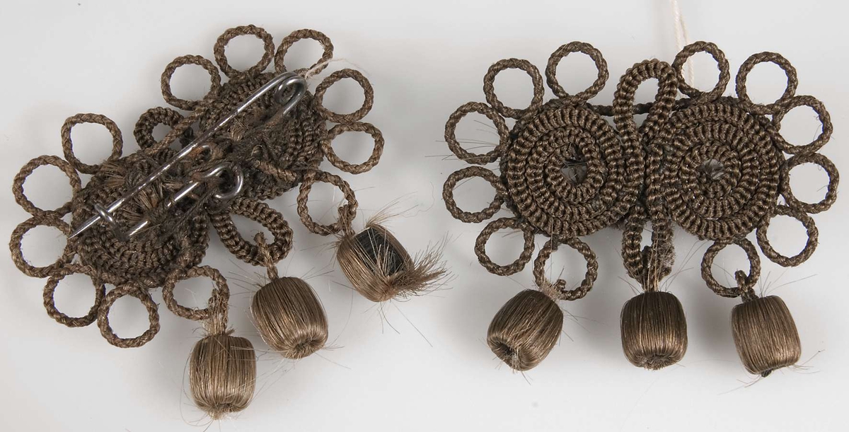 Två broscher, hårarbeten,  tillverkade av brunt hår, monterade på nålar av järn.