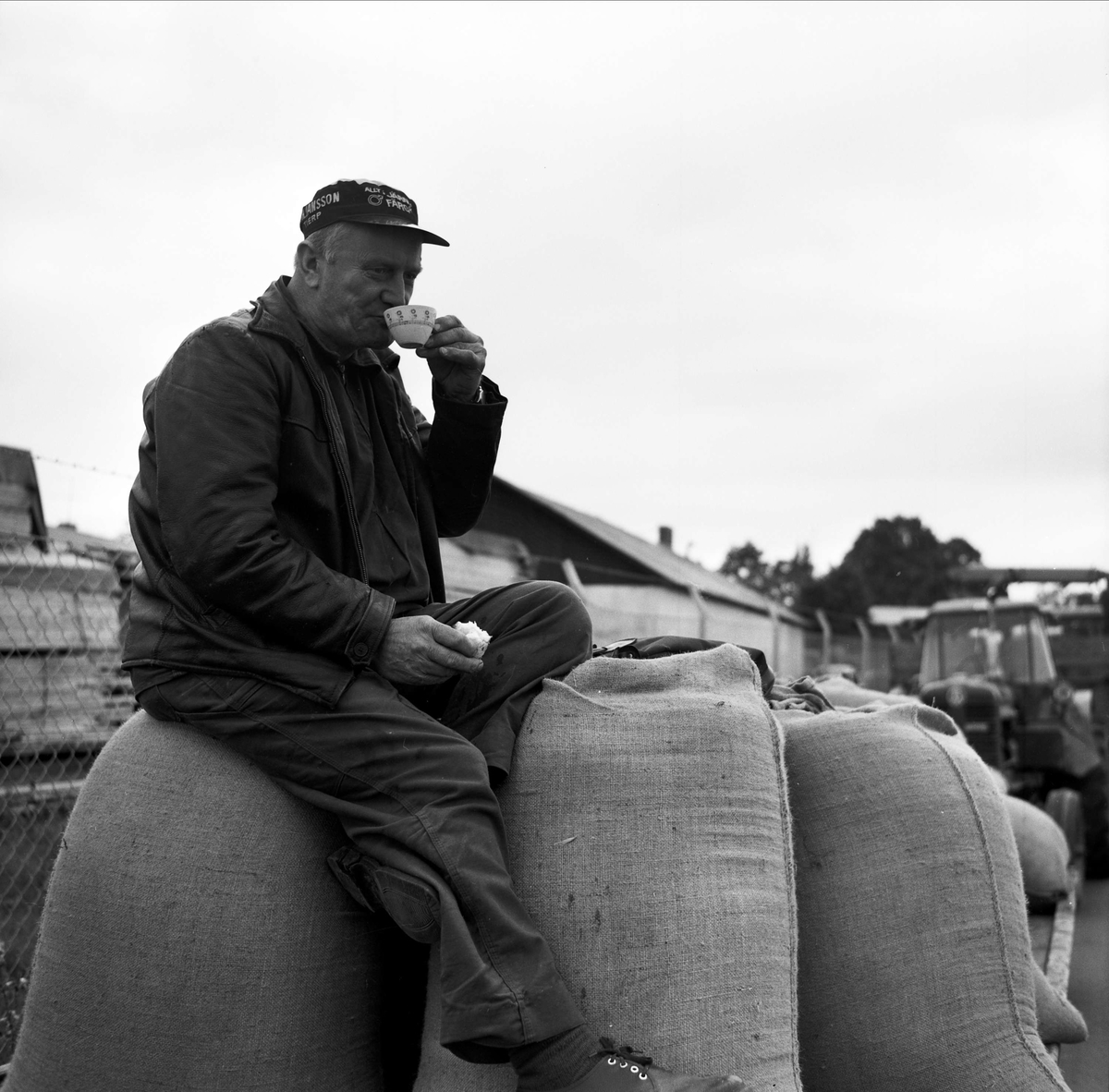Jordbrukare tar kaffepaus sittandes på spannmålssäckar i kön till silon, Tierp, Uppland 1967