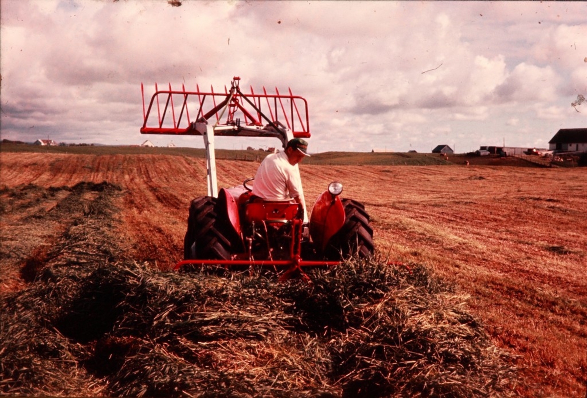 Lasting av gras med Silosvans fra Kvernelands Fabrikk AS, bak- og frontmontert på traktor, bilde tatt bakfra. Fra Jæren.