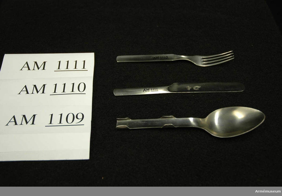 Samhörande nr är 1074-1129, (1109-1111).
Sked m/1929.
Utförd i ett stycke. Skaftet är försett med fyra falsar vilka håller sked, gaffel, och kniv förenade under förvaring och transport. Något speciellt märke för GENSE finns ej på skeden, endast kniven. Har tillhört mob.utrustning vid Armémuseum.