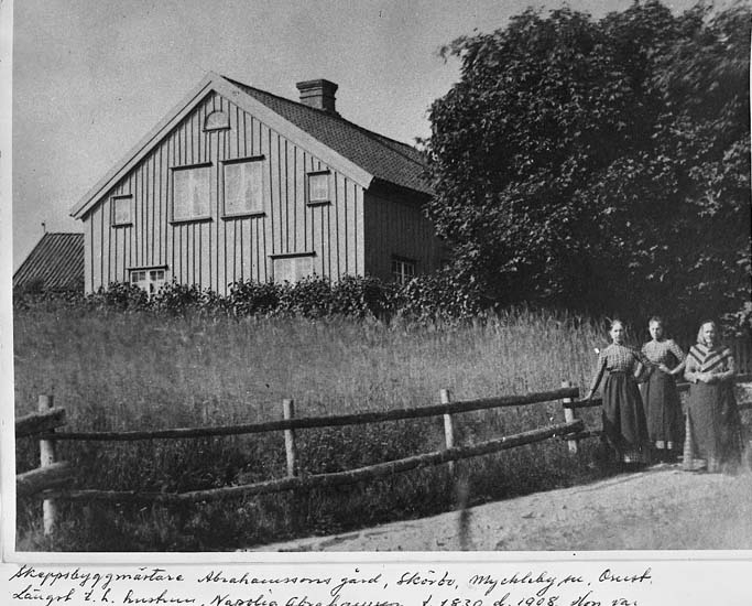 "Skeppsbyggmästare Abrahamssons gård, Skörbo, Myckleby socken, Orust. Längst till höger hustrun Napolia Abrahamsson, född 1830, död 1908. Hon var född Tegner å Buvenäs"