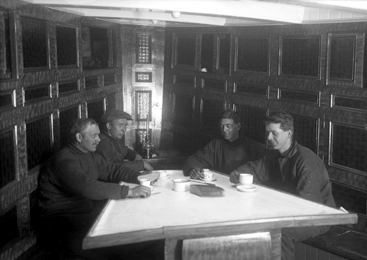 Fyra män dricker kaffe i skansen på en båt