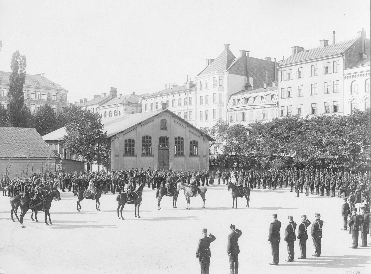 Positionsartilleret A 9 på kaserngården vid Storgatan 1903, soldaterna iförda uniform m/1886. Till vänster spelar musikkåren, i mitten ett flertal officerare till häst.