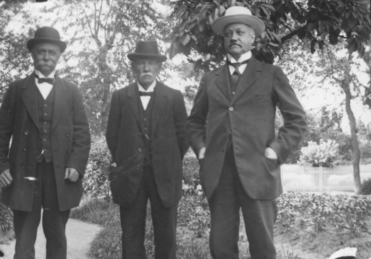 Tre män i en trädgård. Gustav Anderssons far, Johan August, längst till höger.