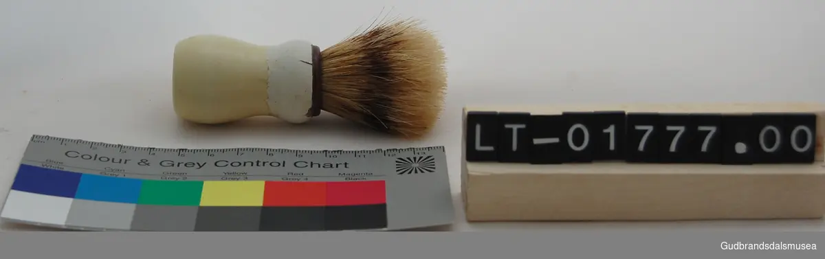 Barberkost av dreid skaft og bust av hår. Hvitt skaft med brun kant ved busten. 