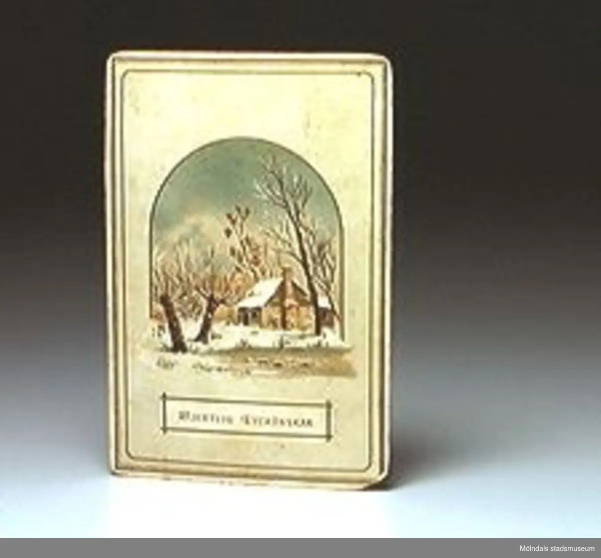 Gratulationskort med bild av snötäckt trädgård med litet hus. Tryckt text på framsidan: "HJERTLIG LYCKÖNSKAN". Minne af J Lundberg till Godtfrid. Signering i bläck på baksidan.