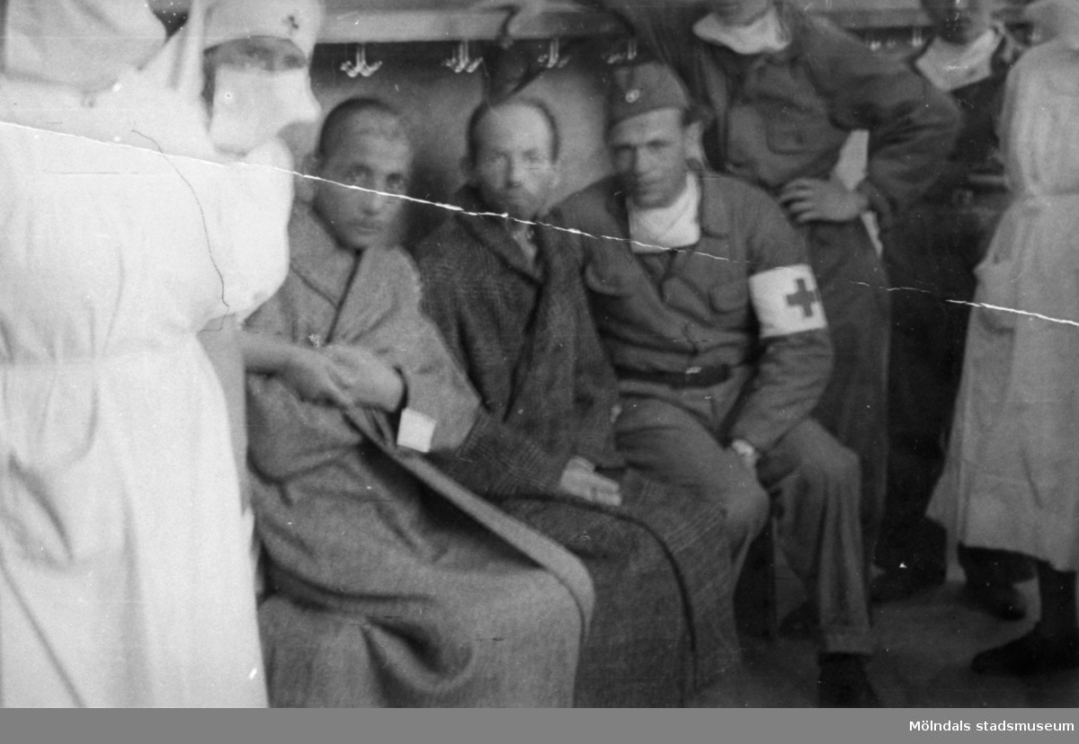 "Karantänsförläggning" på Kvarnbyskolan för överlevande från koncentrationsläger i Tyskland och Polen 1945.  
Skolan fungerade under denna sommar som beredsskapssjukhus.

Två manliga patienter omgivna av Röda Kors personal.