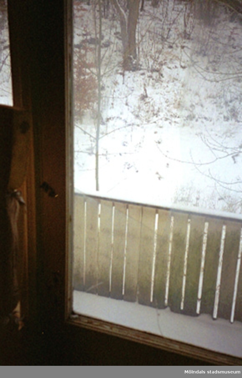 Ett trasigt fönster i Villa Solbacken i Krokslätt, januari 1995. Utanför fönstret finns en veranda med ett staket.