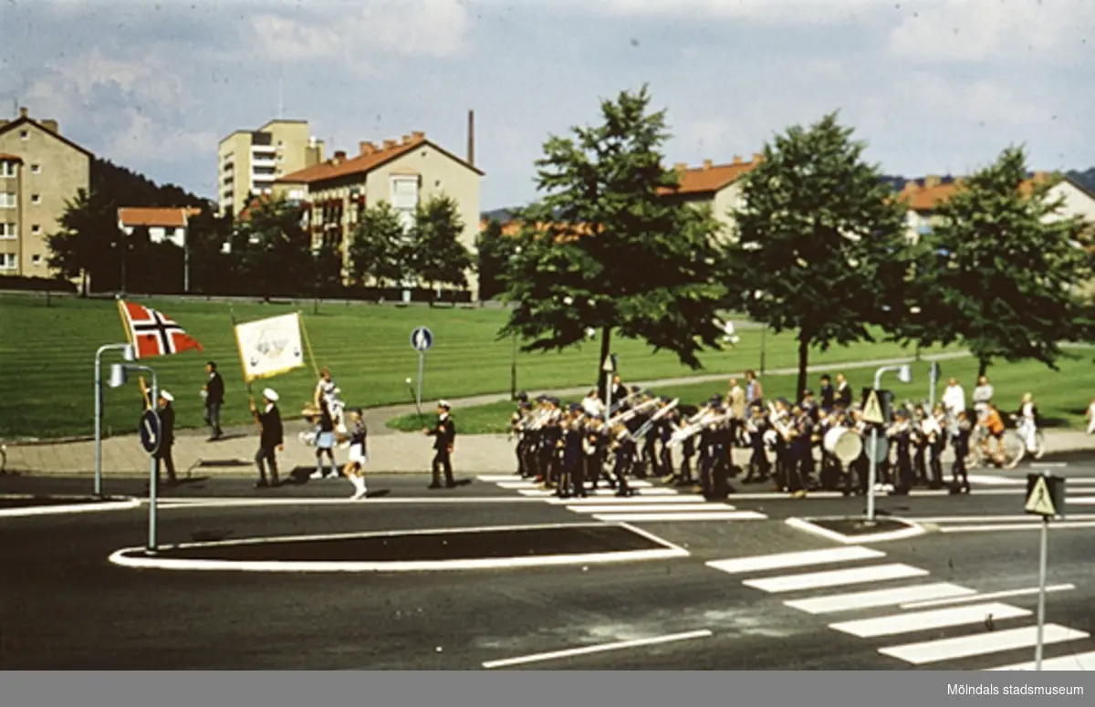 En parad vid övergångsstället på Tempelgatan i Mölndal, år 1970. Man bär den norska flaggan i täten.
Bostadshus i bakgrunden.
