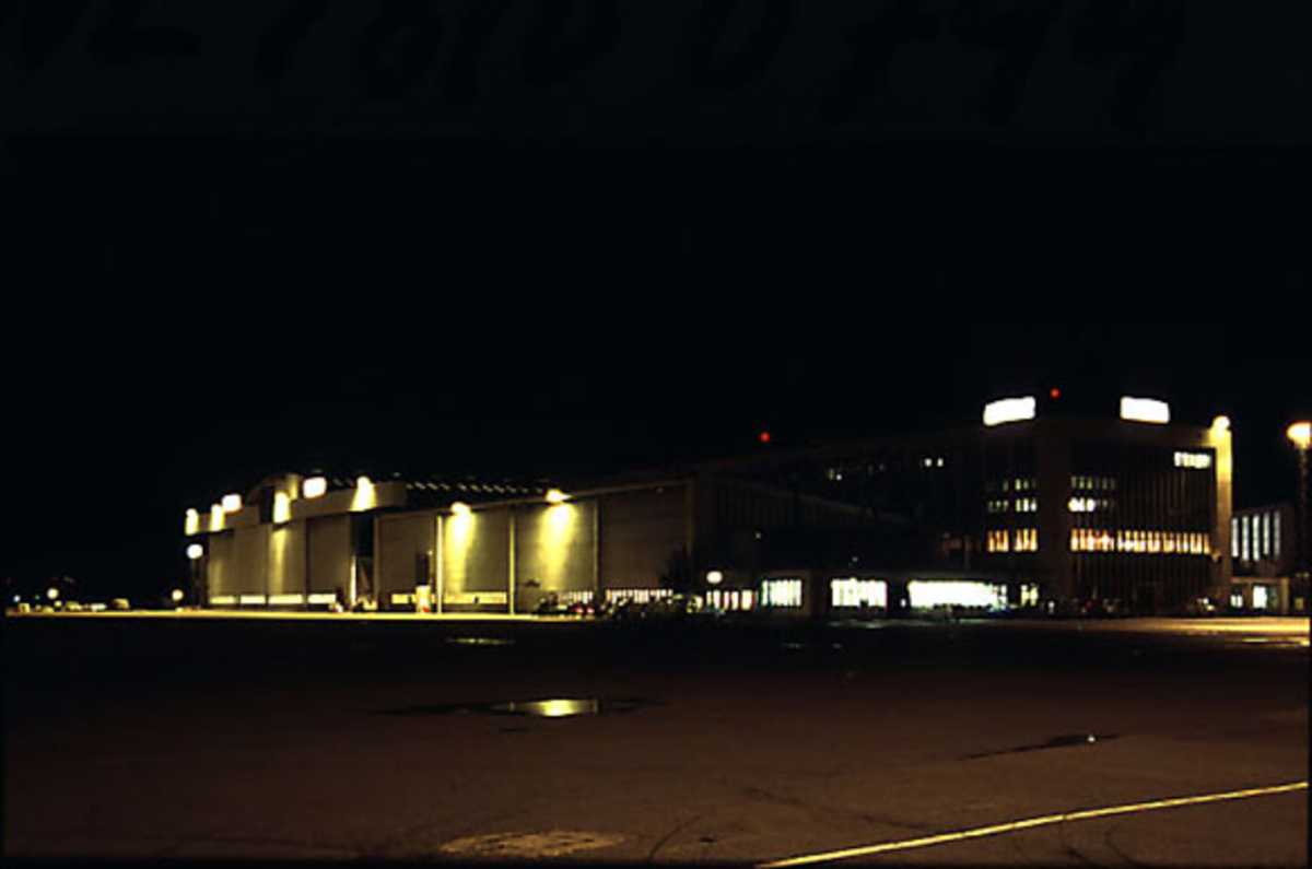 Lufthavn, eksteriørfoto av terminalbygningen. Tatt i mørke.