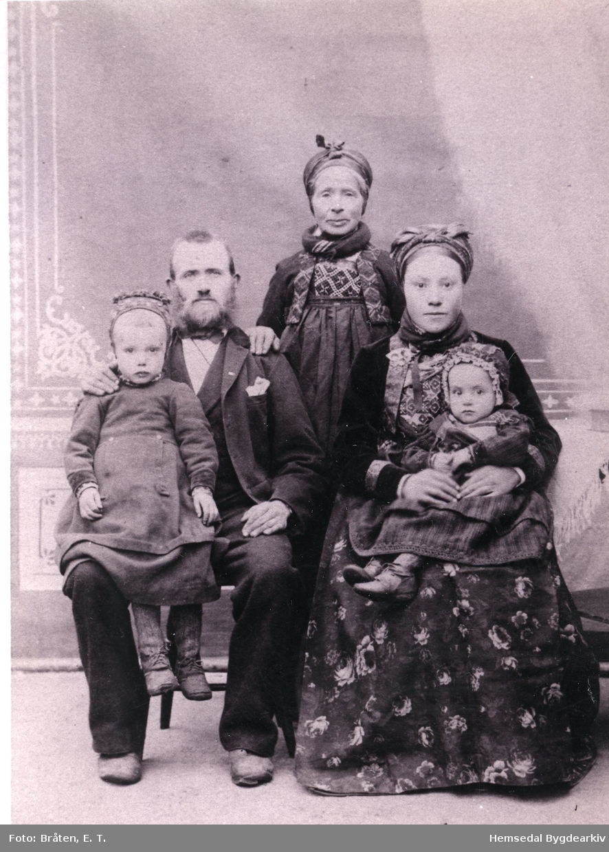Bygdebokskrivaren, Hans  Flaten (1858-1930) og kona hans Birgit Ingvardsdotter Båste (1865--)
Bak dei to står mor til Hans, Margit Håkonsdotter Bergo (1826-1906)
Borna er: Olav, fødd 1888  og Margit, fødd 1889