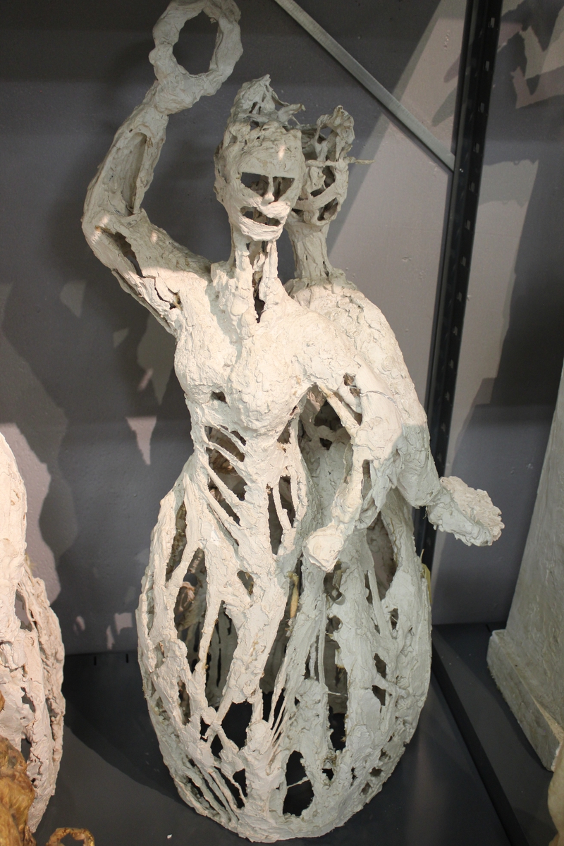 Skulptur i gips av en kvinne med den ene armen over hode, med en ring i handa.. Utkast til "Haldensøylen" 1/3 størrelse. Se også nr.021, nr.212 og nr.213.
Haldensøylen ble laget til byens 300-års jubileum 1965.