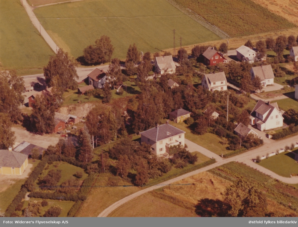 Skråfoto av villabebyggelse på Hellbak i Mysen, Eidsberg 31. august 1960. Søndre Mysens vei.
Bygningen i forgrunnen er Holm Randems Auksjonsforretning.
Daværende eier var Ole J. Randers.