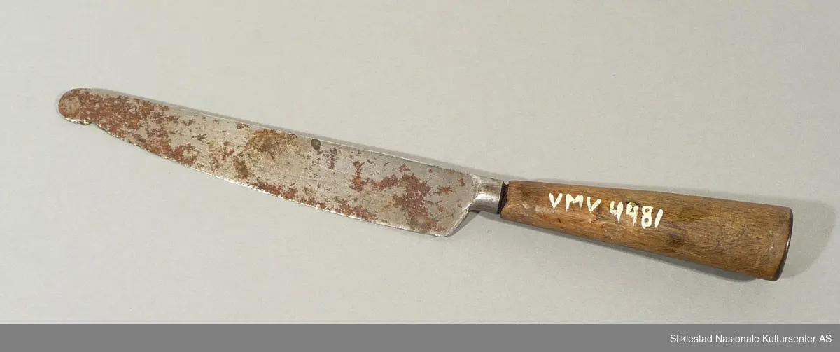 Bordkniv med stålblad og håndtak i tre som er uthullet. Antagelig har det vært "beslag" på toppen? Bladet er rustet, ingen merking. Knivblad stifet fast til skaft, muligens en reperasjon?