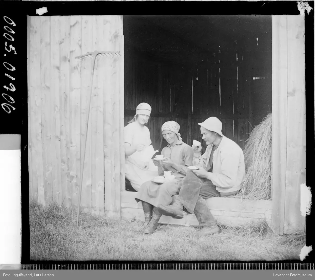 Gruppebilde av en mann og to kvinner som har kaffepause i et uthus.