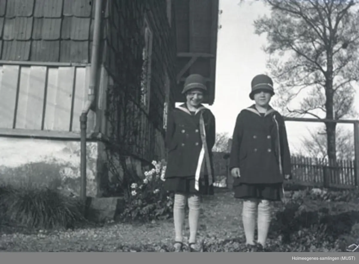To jenter i 17.mai-klær utenfor huset på Holmeegenes i Stavanger.