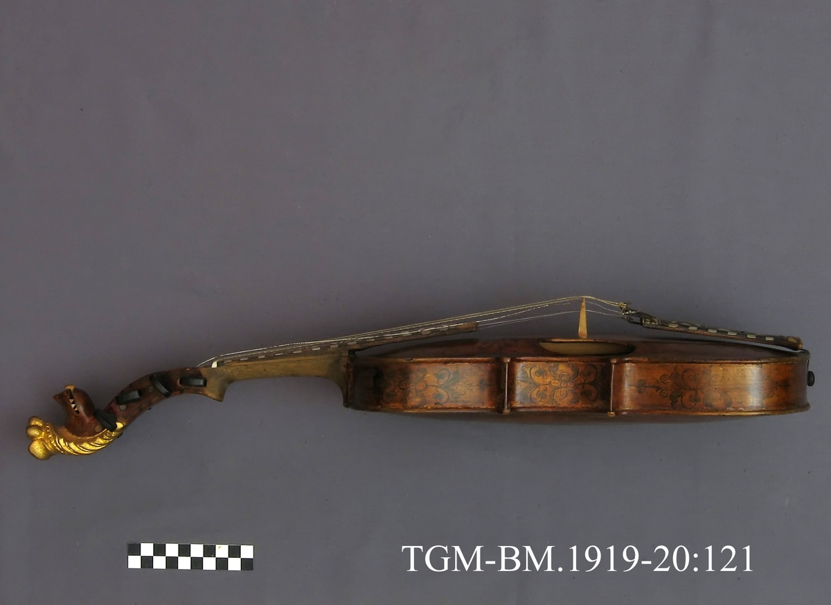 Fra protokollen: Hardingfele av den eldre, smale typen. Bruleggjingi stjerneforma, raud ferniss, stillepinnar og hovud spm vane (Hovudet nygylt). Paa merklappen inni stend: Fabrikeret af Erik Johnsen Helland i Bøe 1838. (Aarstalet ber merke av aa vera retta, serleg seinste siffer; papiret under aarstalet er vekkskrapa og talet uppnya paa berre treet.). Lok av gran, trojsk av hegg, botn av svartor, hovud av bjørk.