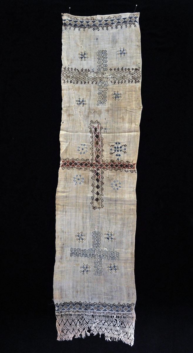 Fra protokollen: Likkisteklæde. Hvitt linklæde med et stort kors syet midt paa. I hver ende av klæde to border, og en knyttet fletning (som paa haandklæder). Korset er fyldt med krokmønster av av kulørt uldsøm, samme mønster i borden.