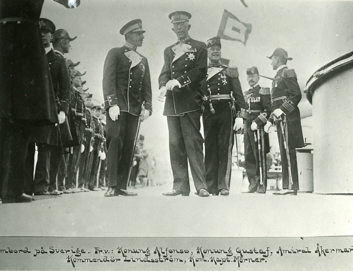 [textat på monteringsbas under det avfotograferade fotografiet:] "Ombord på Sverige. Fr.v.: Konung Alfonso, Konung Gustaf, Amiral Åkermark Kommendör Lindsström, Kom.Kapt. Mörner."