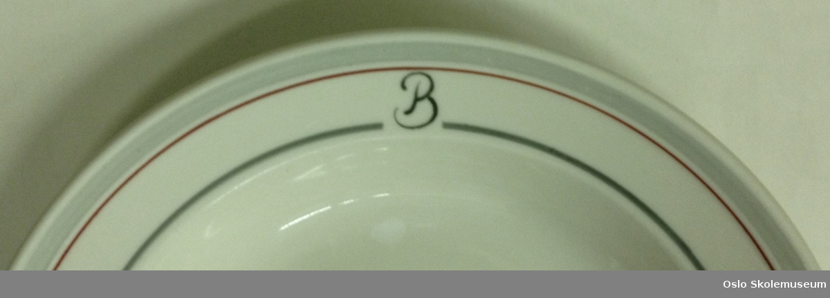 Dyp tallerken med dekorstriper. Den er merket med bokstaven B.