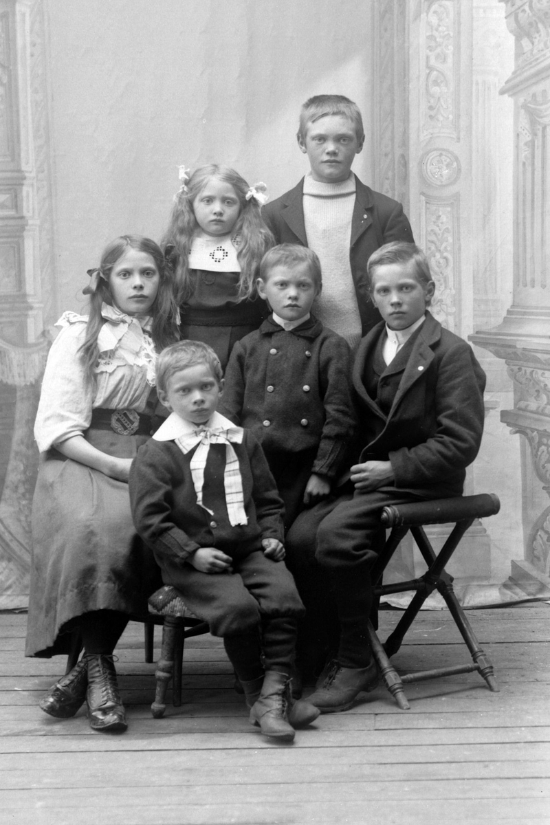 Studioportrett av seks barn i helfigur, trolig barna til ekteparet Eliassen.
