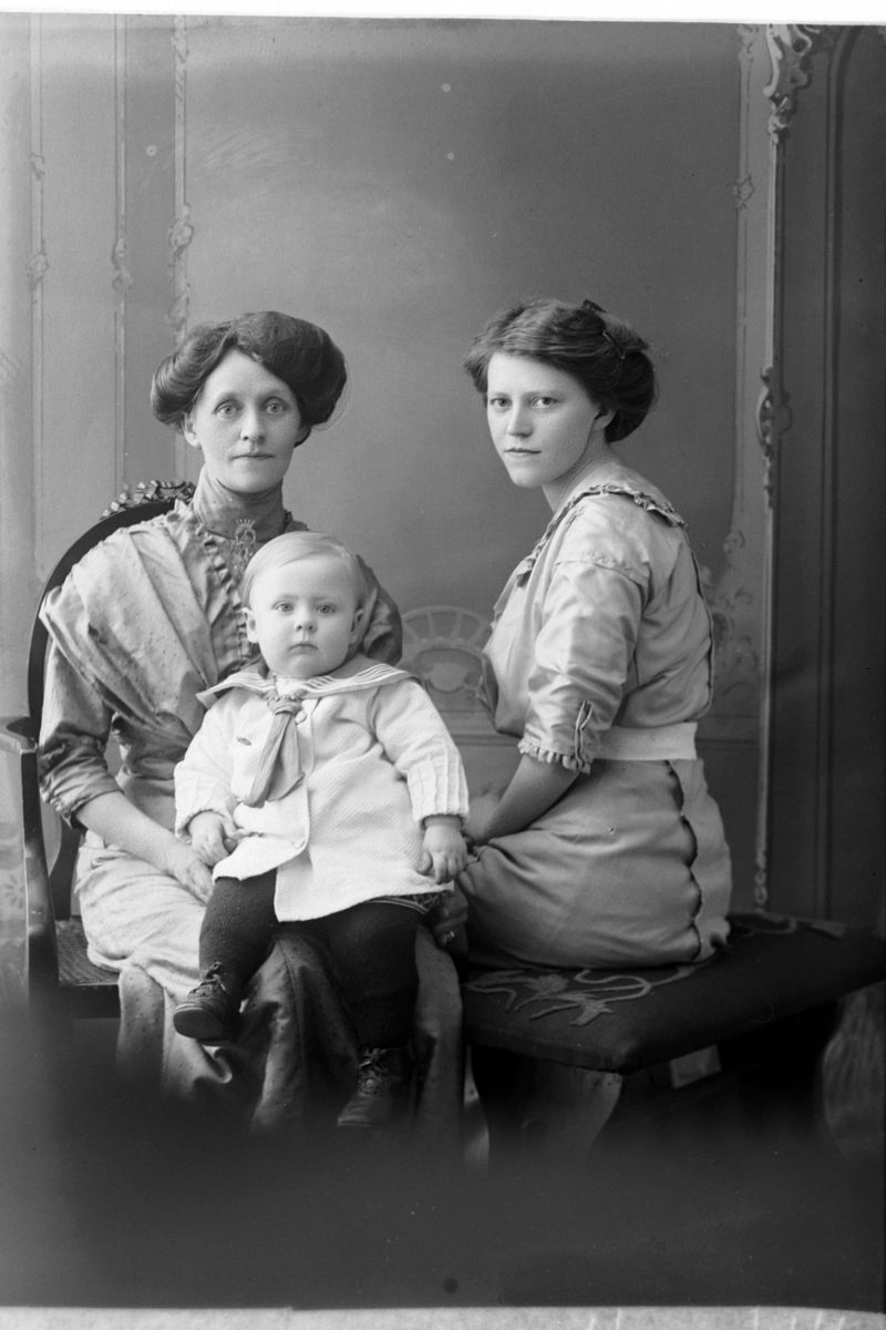 Studioportrett av to kvinner med et barn i matrosdress.
