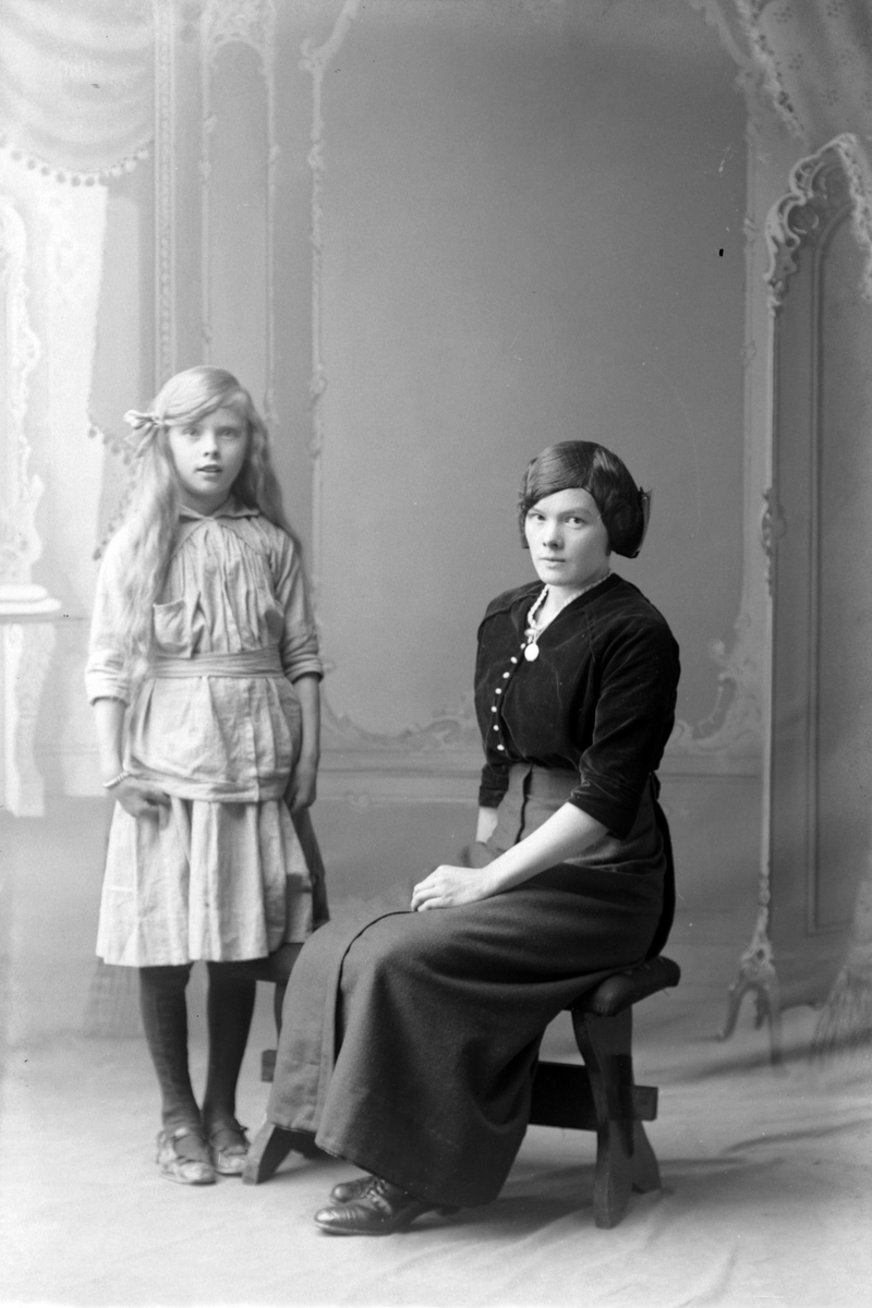 Studioportrett av en ung kvinne ved siden av en jente.