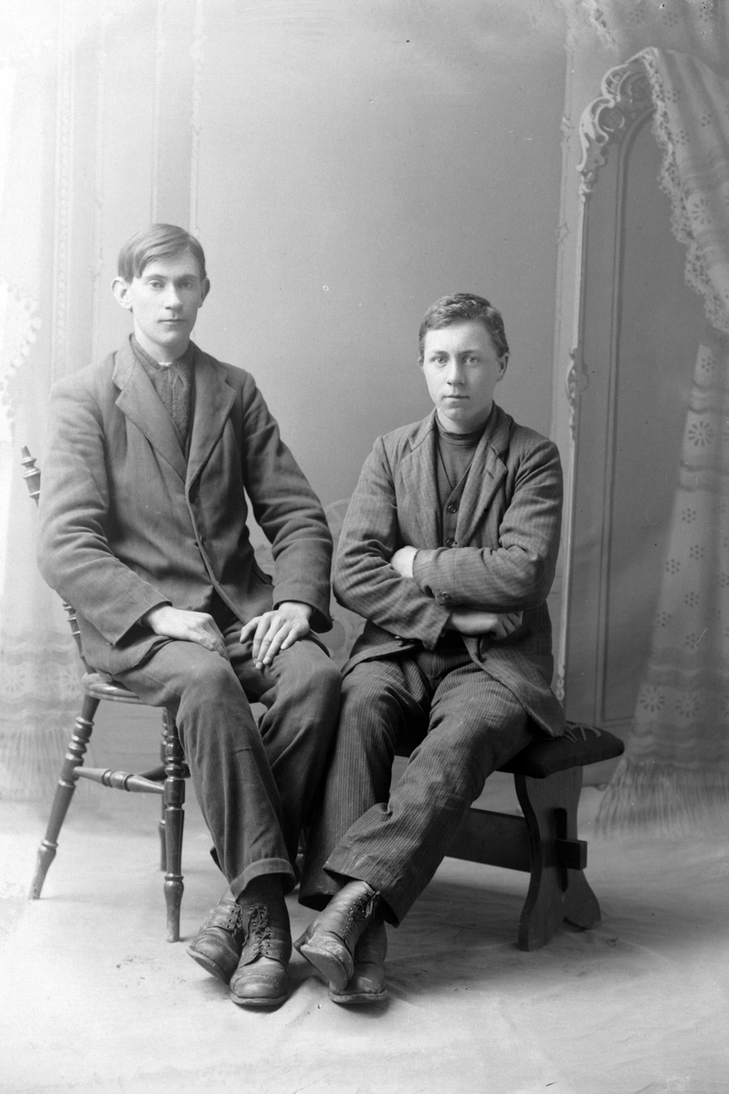 Studioportrett av to menn som sitter.