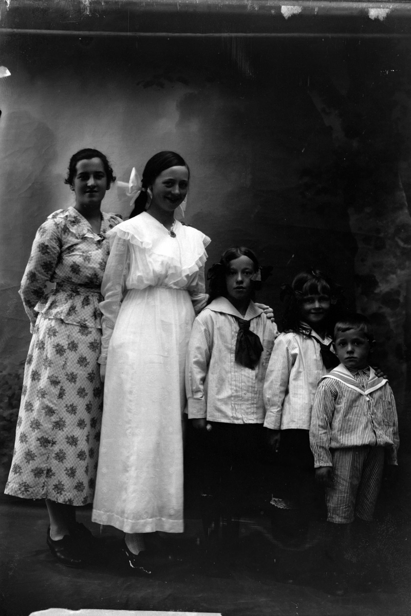 Studioportrett av to kvinner og tre barn stilt på en rekke.