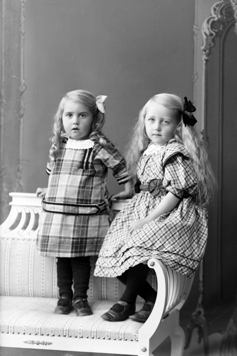 Studioportrett av to jenter på en benk.