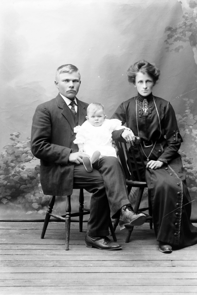 Studioportrett av en kvinne og mann med et barn på fanget.