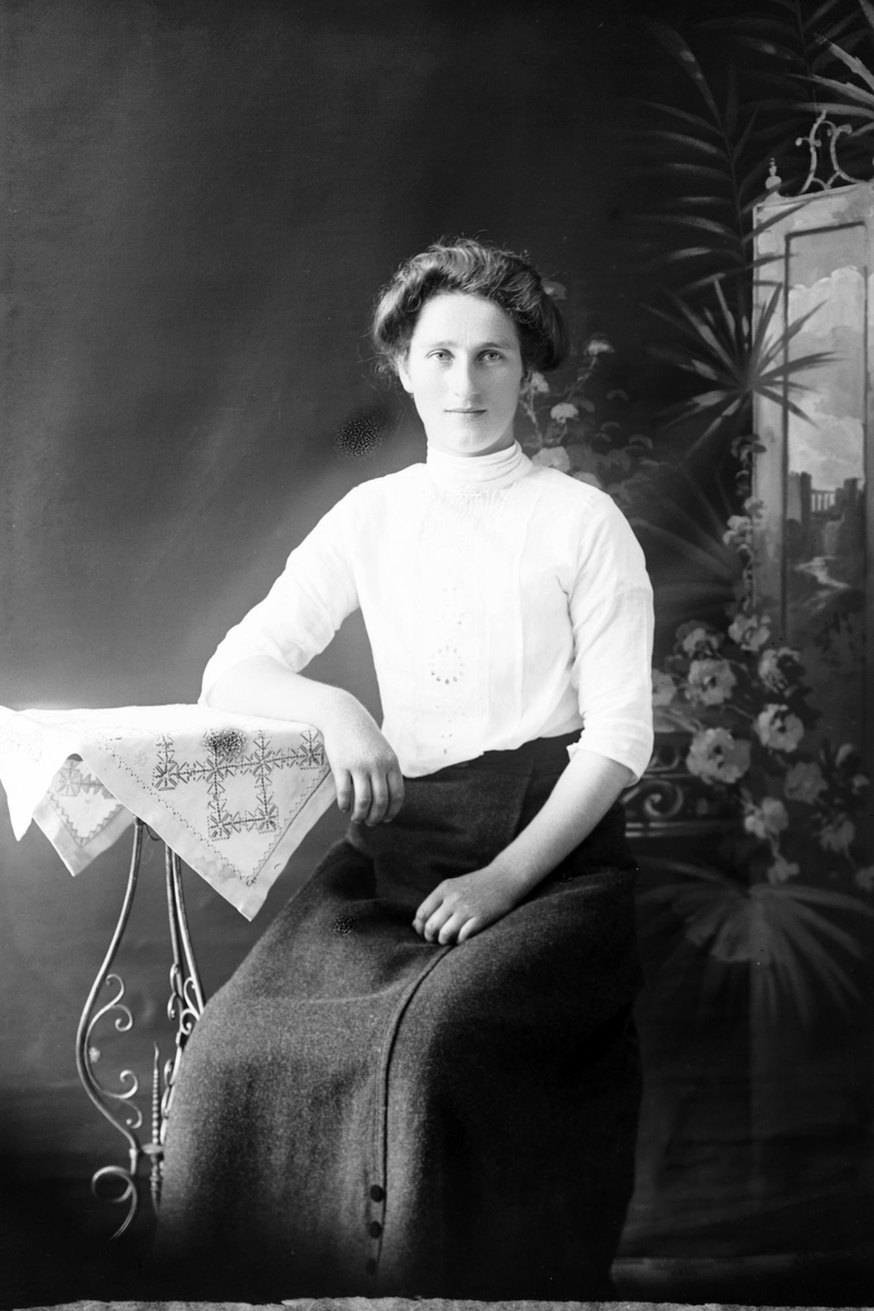 Studioportrett av en kvinne som lener armen på et bord.